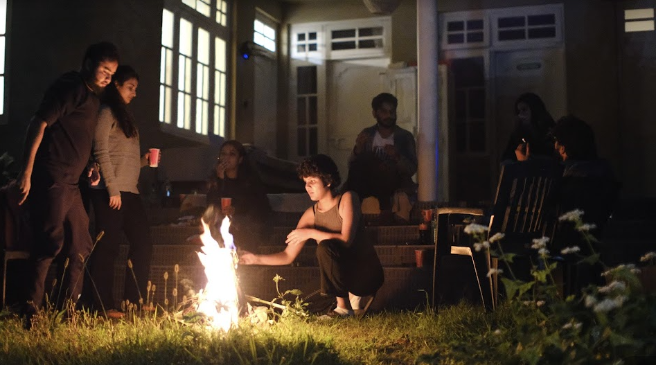 The image shows digital nomads in India enjoying around a bonfire