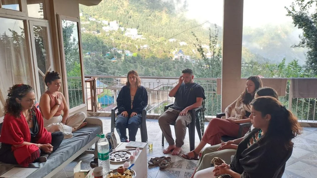 The image shows a group of people sitting at a coliving space in Dharamkot Himachal PRadesh India